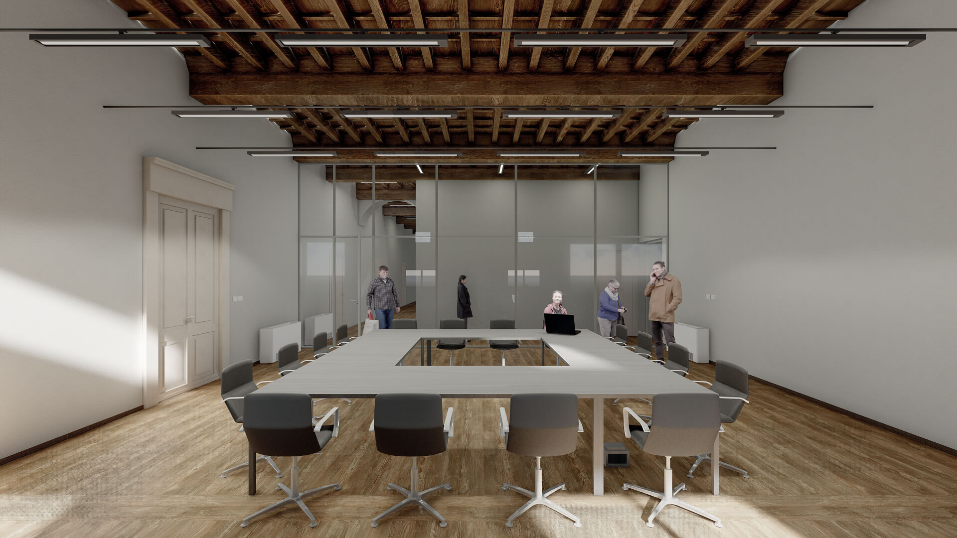 Sala riunioni ricavata all’interno di ambiente storico restaurato con soffitto ligneo a travi e tavolato a vista, pareti intonacate e pavimentazione in legno. Al centro dello spazio è disposto un grande tavolo quadrato con sedute contemporanee per uso conferenze, mentre sul fondo una parete vetrata a tutta altezza delimita un ulteriore ambiente mantenendo la continuità visiva. L’illuminazione tecnica lineare sospesa sotto la struttura del solaio e la presenza di porte storiche restaurate evidenziano l’intervento di riqualificazione che integra nuovi elementi funzionali all’interno dell’architettura esistente destinata a uso direzionale o istituzionale.